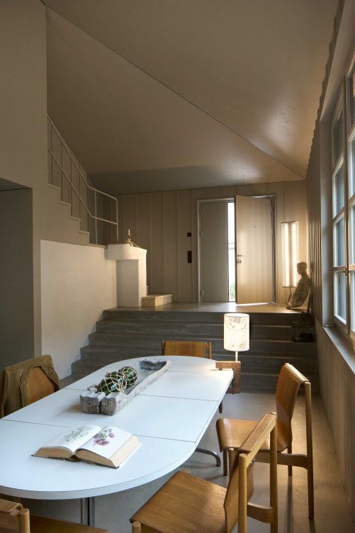 Eine elegante Steintreppe führt in die Küche hinunter. Der helle, offene Raum kommuniziert über die grosszügigen Fenster mit dem Garten.