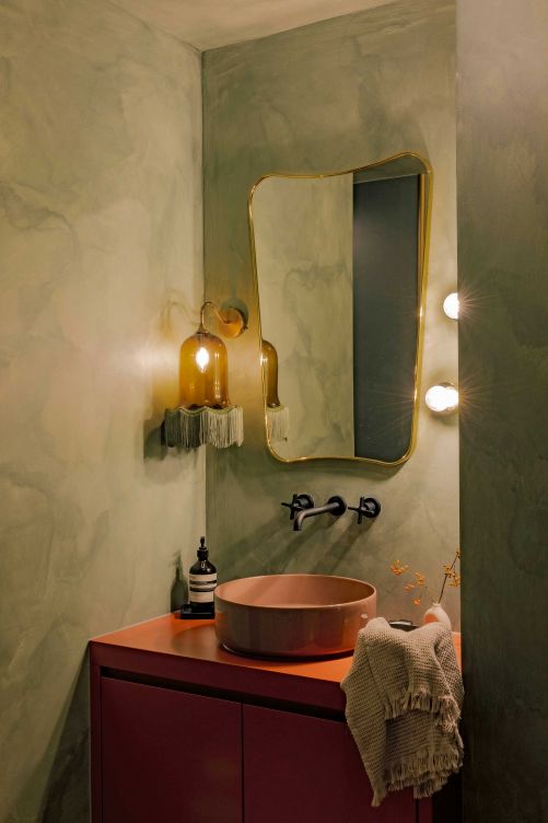Das Bad mit Dusche und WC erinnert mit seinen Farben an die golden verfärbten Föhrenwälder im Herbst. Wandspiegel: «F.A. 33» von Gubi. Leuchte: «Vintage Bell» von Rotschild & Bickers.