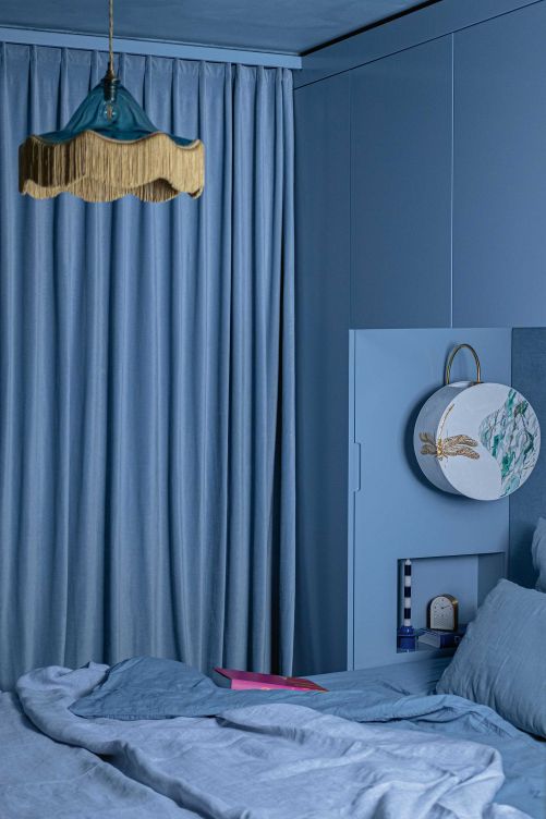 Ganz in Blau ist das Schlafzimmer gehalten – als Reminiszenz an die Farbe des Crestasees. Der Blick geht dabei ins Grüne. Deckenleuchte: «Vintage» von Rotschild & Bickers.