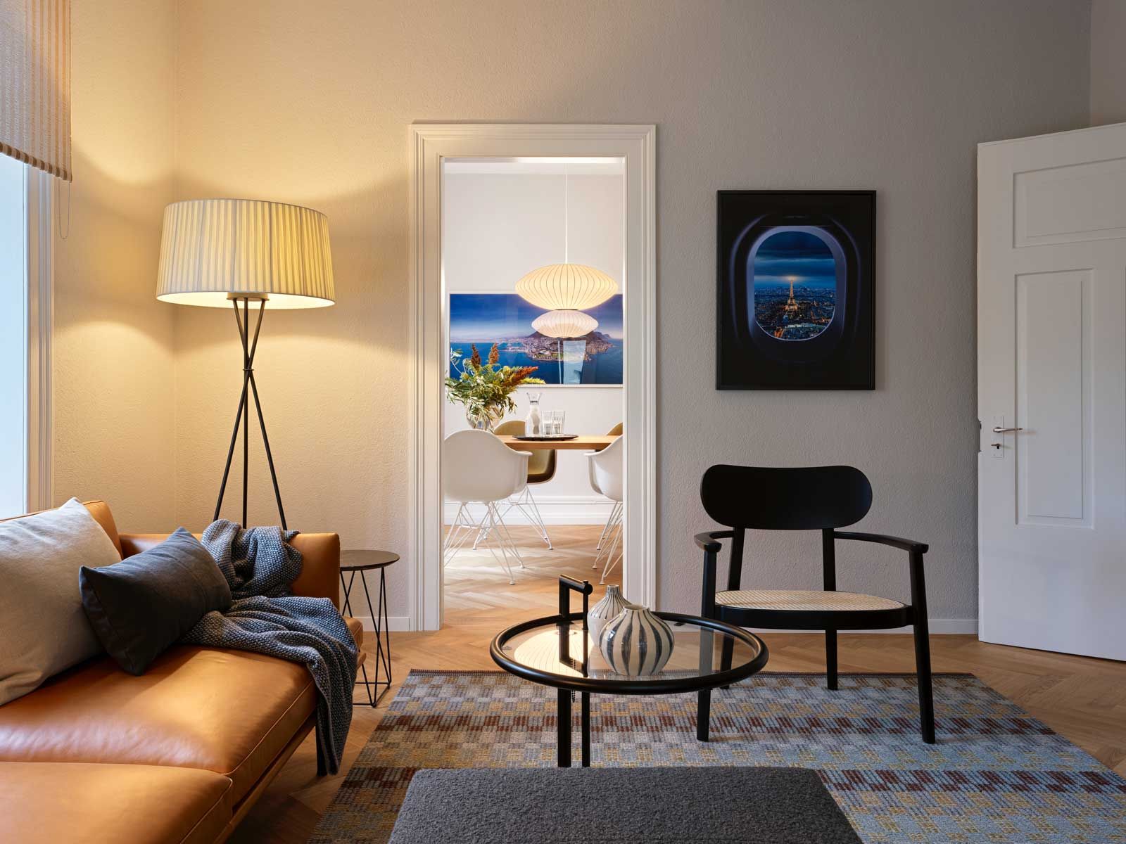 Der Blick vom Wohnzimmer ins Esszimmer zeigt, wie eine ausgehängte Tür Räume öffnen kann. Tisch «Ultimo» von Tossa, vier «Eames Chairs» und die Pendelleuchten «Saucer ­Bubble» stehen im Raumverbund mit dem Wohnzimmer.