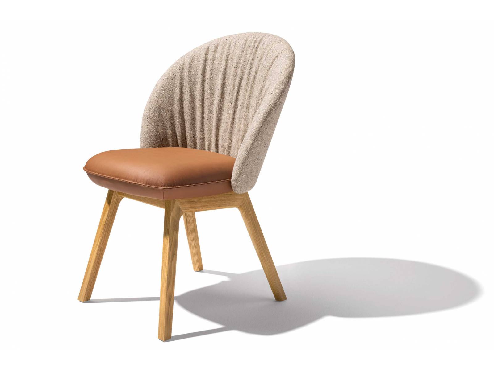 «Flor» ist ein Garant für Komfort und Wohnlichkeit. Ein schönes Detail bei diesem Stuhl ist der raffinierte Faltenwurf auf der Innenseite der Rückenlehne. Mit Textil bezogen, bildet diese einen attraktiven Kontrast zur Sitzfläche in Leder. TEAM 7.